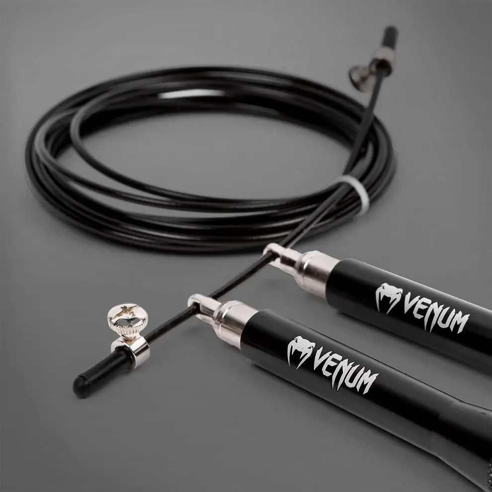 Šokdynė Venum Thunder EVO - Juoda Juodos spalvos greičio šokdynė Venum Thunder EVO su metalinėmis rankenomis, reguliuojamu plieniniu trosu ir fiksavimo varžtu stambiu planu.